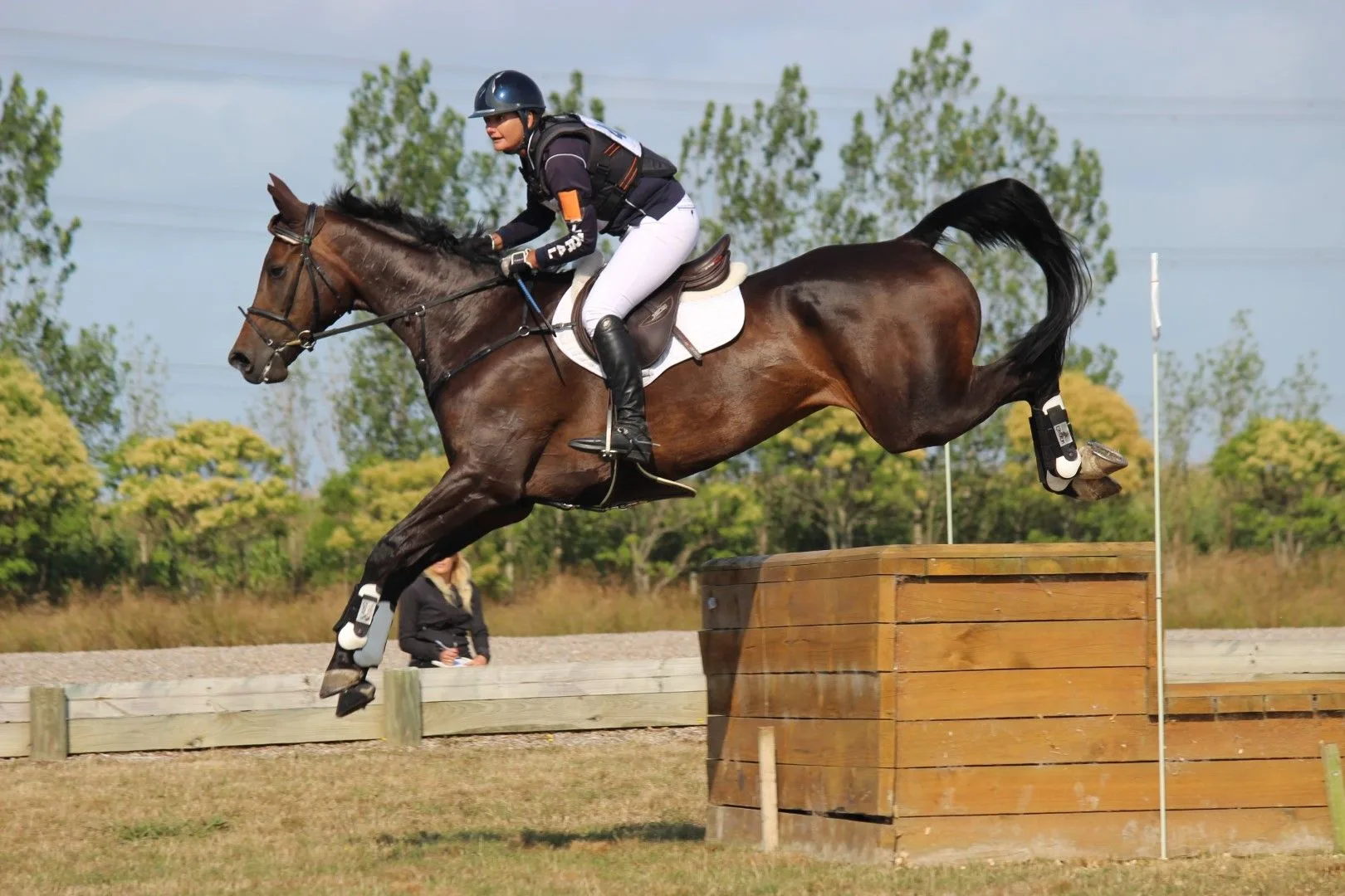 Simone Kann riding cross-country over a timber table fence