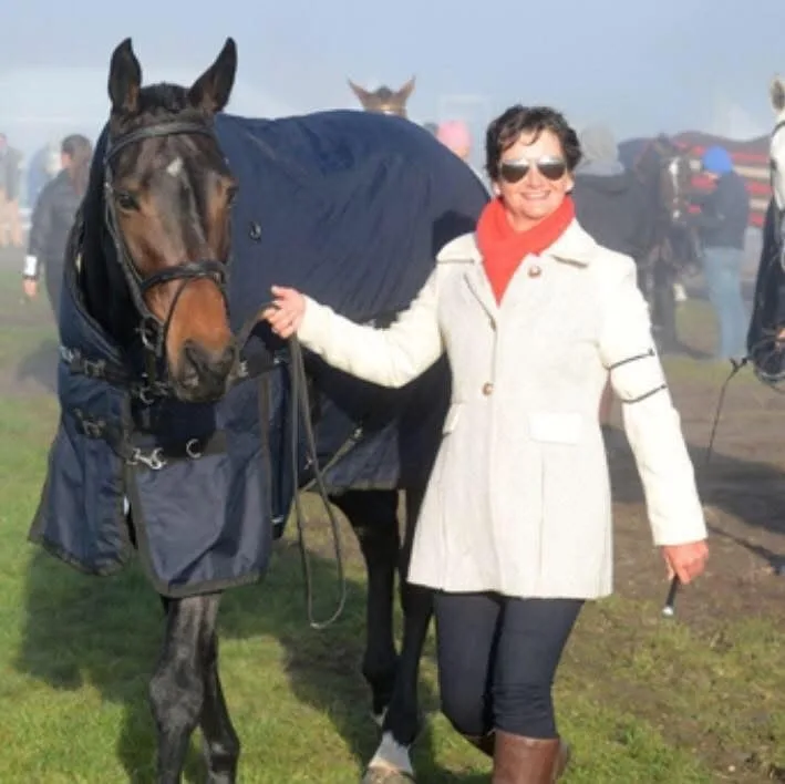 Simone Kann leading a rugged bay horse at a competition