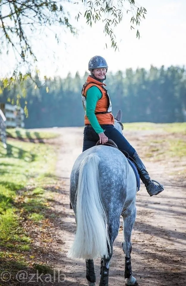 Simone Kann riding a dapple grey horse out along a farm track
